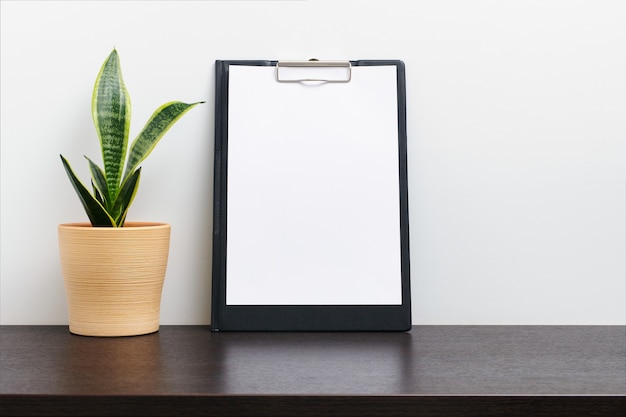 Black clipboard mockup wtih cactus in a pot on dark workspace table and white background