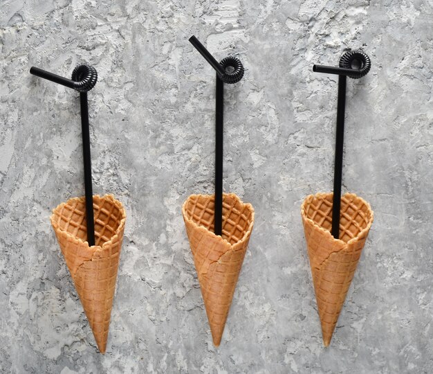 Photo black cocktail tubes in waffle horn on a concrete table, top view, flat lay, minimal trend