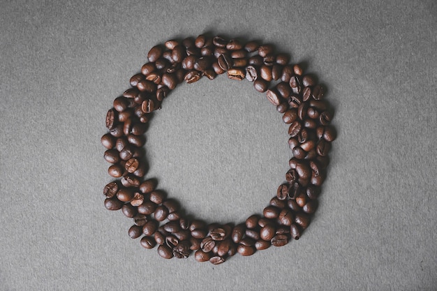 灰色の背景の上の円のような形をした黒いコーヒー豆