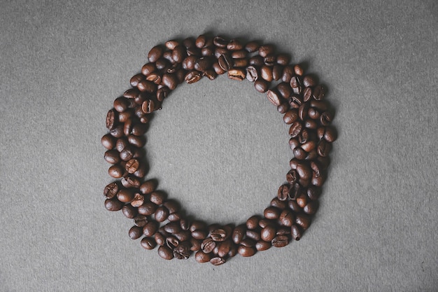 Black coffee beans shaped like a circle on grey background