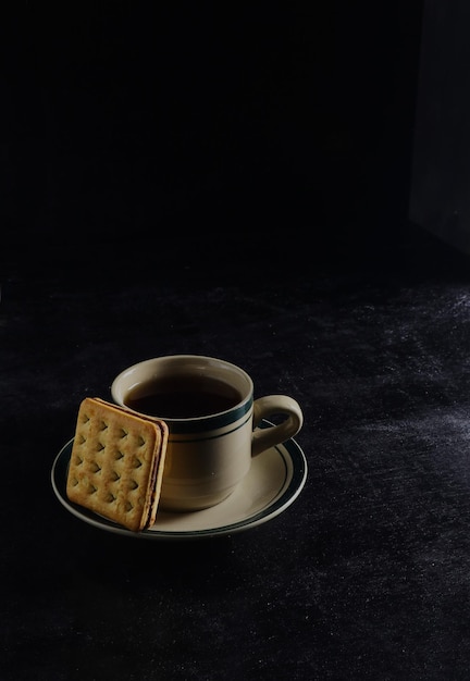 Black coffee and biscuits on the black background