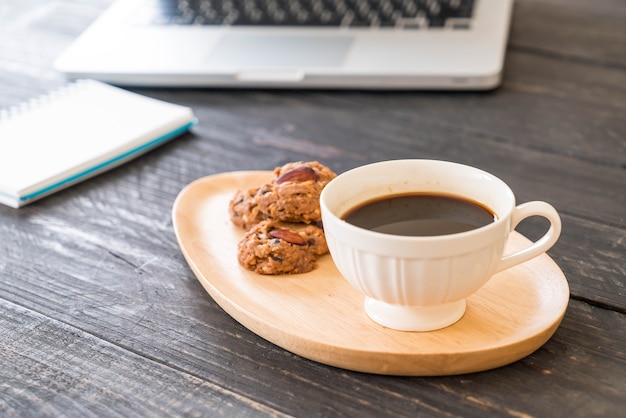 ラップトップとノートブックを備えたブラックコーヒーとクッキー