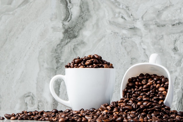 Black coffee in cup and coffee beans on marble