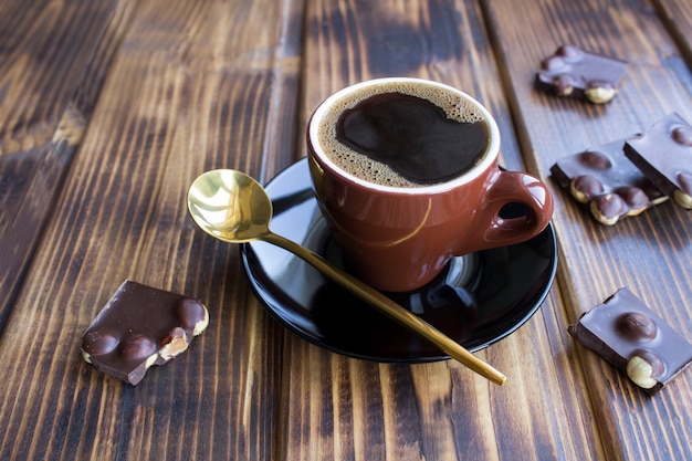 カップのブラックコーヒーとヘーゼルナッツ入りダークチョコレート