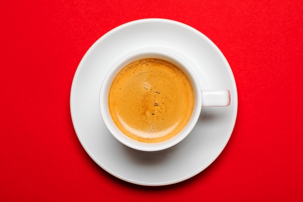 Black coffee in a cup on a red surface