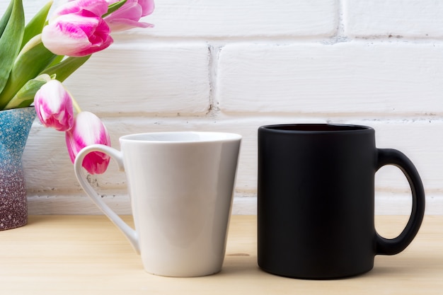 Black coffee cup and white latte mug with magenta tulip