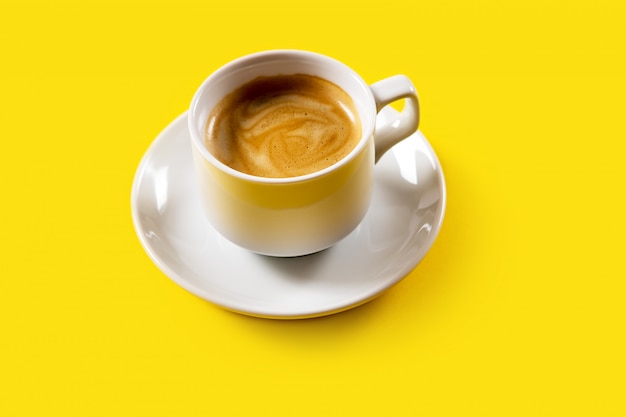 Black coffee in a cup on yellow