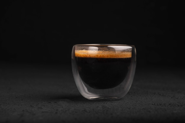 Photo black coffee in a glass on a dark background