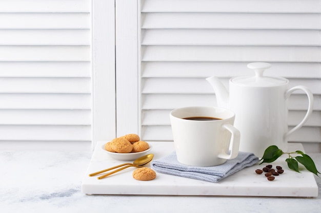 Black coffee in mugs with coffee pot on marble cutting board White background Copy space