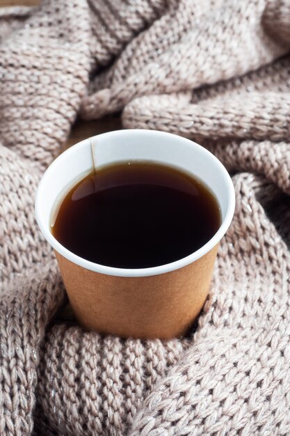 Black coffee in a paper cup on the background of a warm blanket. flat lay copy space, top view.