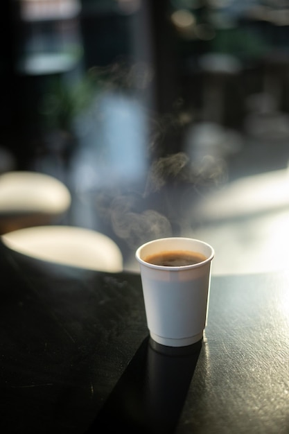 black coffee on a paper cup served on white table at cafe