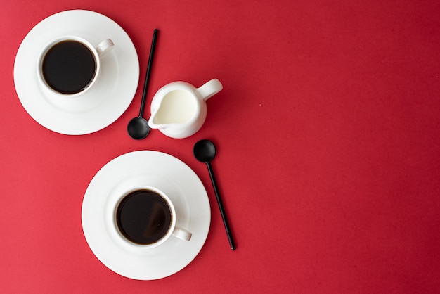 Black coffee in a small white coffee cup on a red background