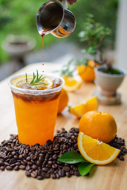 Photo black coffee top on fresh orange juice on wooden table