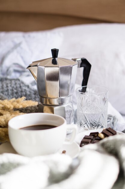 Black coffee in white cup in bed