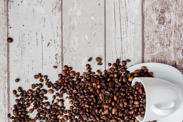 Black coffee in white cup and coffee beans on light wooden background. Top view, copyspace