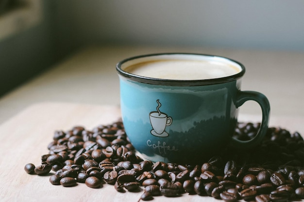 Black coffee in white cup on freshly roasted coffee beans background Top view