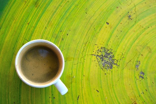 Photo black coffee in white cup on green background