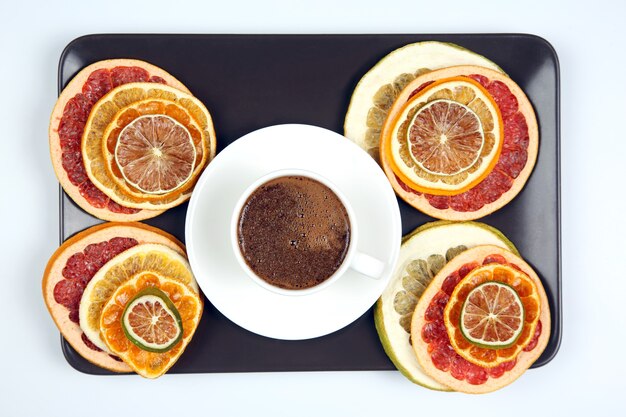 Black coffee in a white Cup surrounded by citrus dried fruits