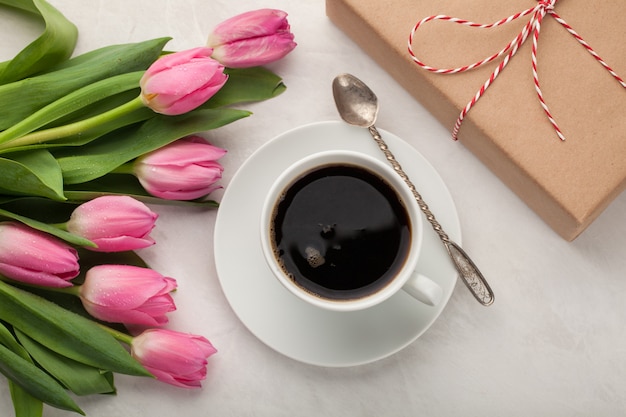 Caffè nero in tazza bianca e tulipani.