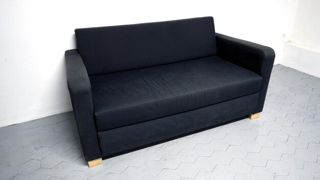 Black color sofa that made from wood and fabric in the white room and grey floor and no people