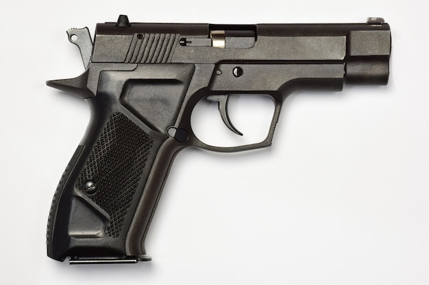 Черный боевой пистолет на белом фоне отсечения. Крупным планом вид сбоку, место для вставки надписи