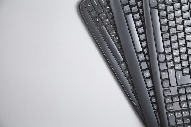 Black computer keyboards on grey background.