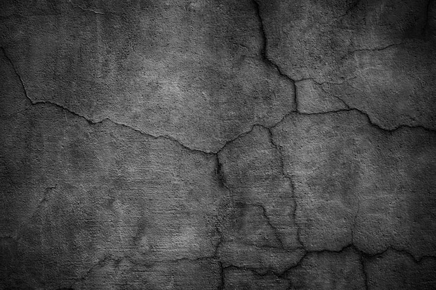 Black concrete wall covered with cracks.