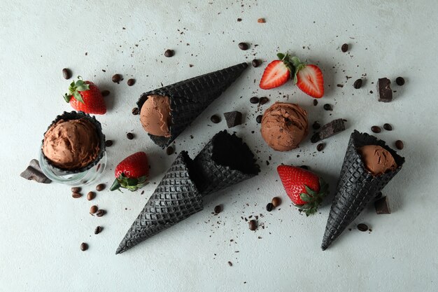 Black cones with ice cream and ingredients on white textured