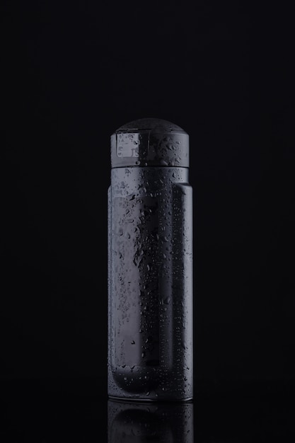 Foto contenitore nero per liquidi e shampoo su sfondo nero