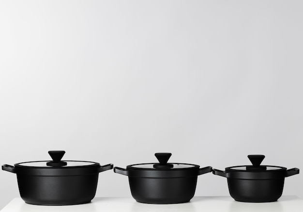 Black cooking pots on grey background front view