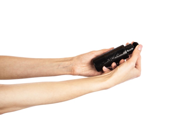 Black cosmetic flip top bottle in female hands isolated on white background