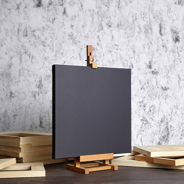 Black cotton canvas on a wooden easel and stretcher bars on table