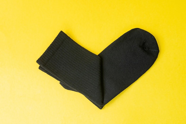 Black cotton socks are lying on a yellow table