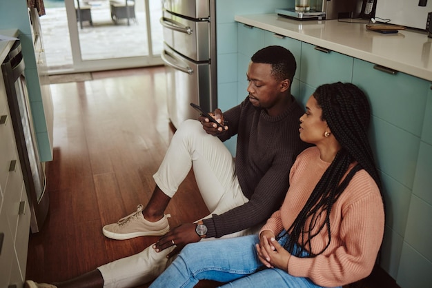 Photo black couple phone and kitchen floor while online on internet together for social media or ecommerce young man and woman talking while at home to bond relax and use wifi for communication app