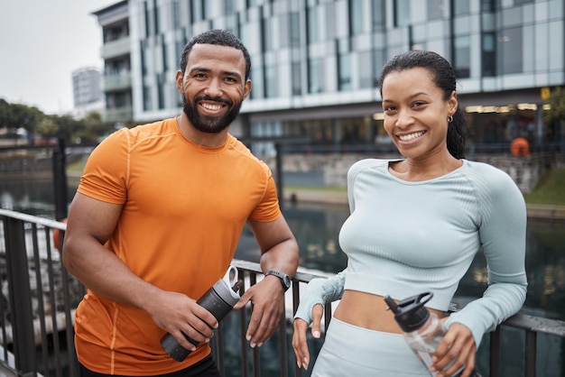 Портрет черной пары и фитнес в городском городе, партнер по тренировкам с бутылкой воды для увлажнения и отдыха после тренировки Счастливый черный мужчина с черной женщиной и велнес-активный образ жизни в Чикаго