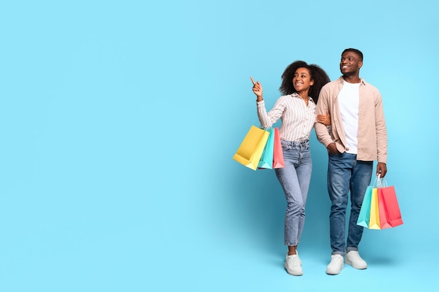 Photo black couple shopping with colorful bags on blue background