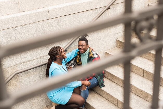 Photo black couple sitting on a stairs in the city.