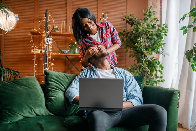 Black couple with laptop having fun on sofa