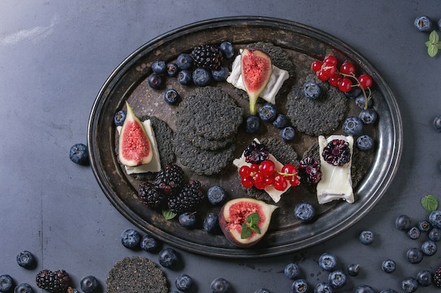 Black crackers with cheese and berries