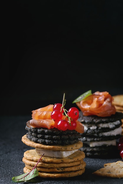 Black crackers with salmon and berries