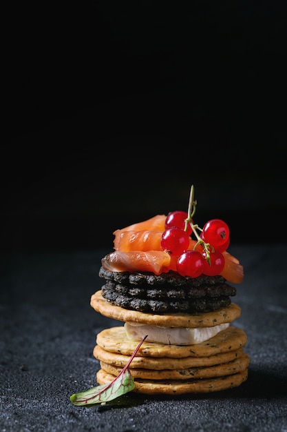 Black crackers with salmon and berries