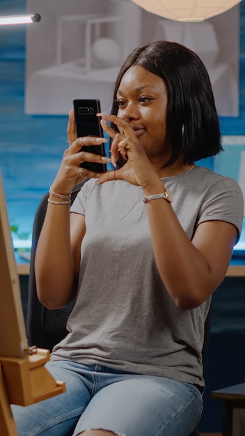 Black creative person holding smartphone for pictures of art drawing