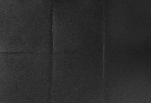 Black crumpled unfolded paper sheet texture background Paper folded in six Full frame