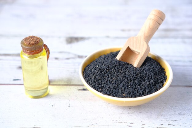 Black cumin in a bowl with oil in a jar on table