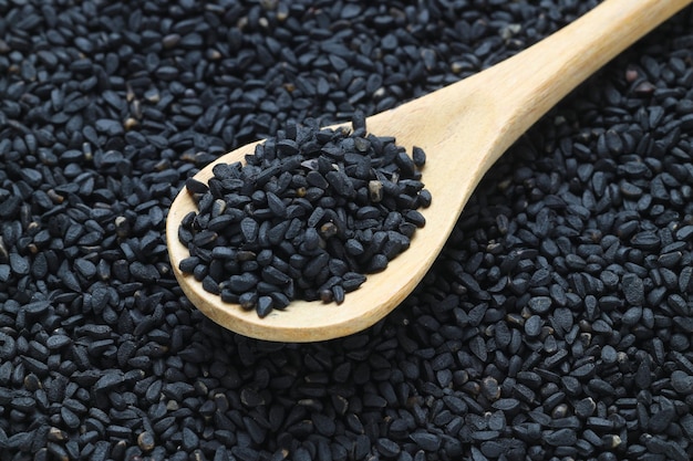 Black cumin seeds and essential oil with bowl and wooden shovel or spoon Nigella Sativa