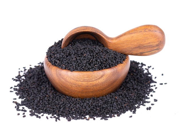 Black cumin seeds in wooden bowl and spoon isolated on white background Heap of black nigella seeds Nigella sativa