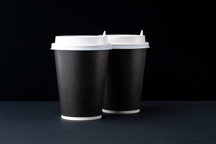 黒の背景に白いキャップとコーヒーの黒いカップ