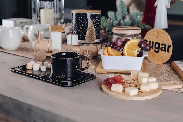 Black cup, food and New Year decorations are on the table in the room. New Year eve concept