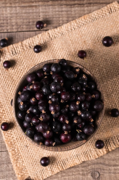 Black currant in a bowl on wooden background Organic berries