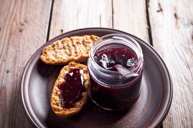 Black currant jam in glass jar and crackers